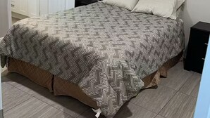 Un dormitorio con una cama, ventilador de techo, ventana con persianas, cómoda y espejo.