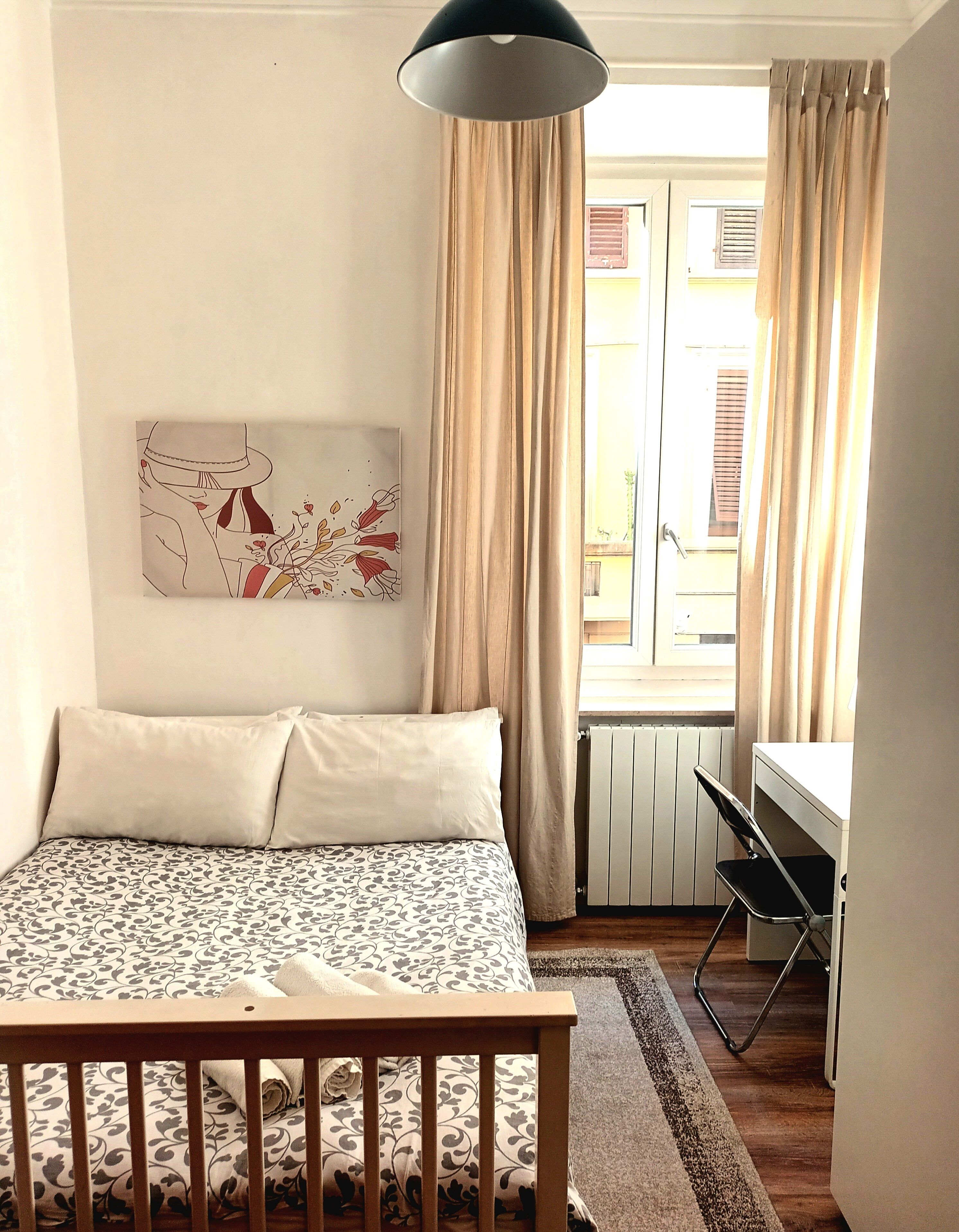 Une chambre à coucher avec un lit, un bureau et une fenêtre avec des rideaux.