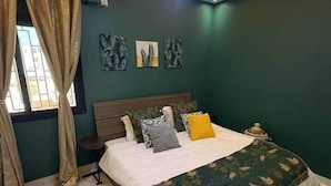 A bedroom with a bed, curtains, a nightstand, and wall art. - Bright Designer 2BR/3BA | Balcony | Washer | Almadies (Dakar)