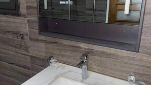 Ein Badezimmer mit einem weißen Waschbecken, einem Spiegel und Holzpaneelen an der Wand.