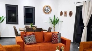 Ein modernes Wohnzimmer mit einer Sofagarnitur, einem Couchtisch und einem Essbereich im Hintergrund.