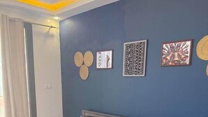 Une chambre à coucher avec un lit, des oreillers, une table de chevet et des œuvres d’art murales.