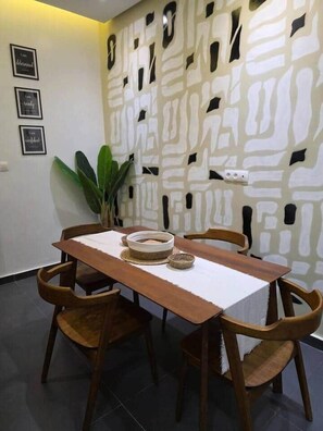 Ein Essbereich mit Holztisch und Stühlen, einer Wand mit dekorativen Ausschnitten und einem Blumentopf.