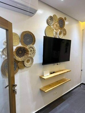 Ein modernes Wohnzimmer mit einem flachbildfernseher an der Wand, umgeben von dekorativen Wandbildern aus Gewebe.