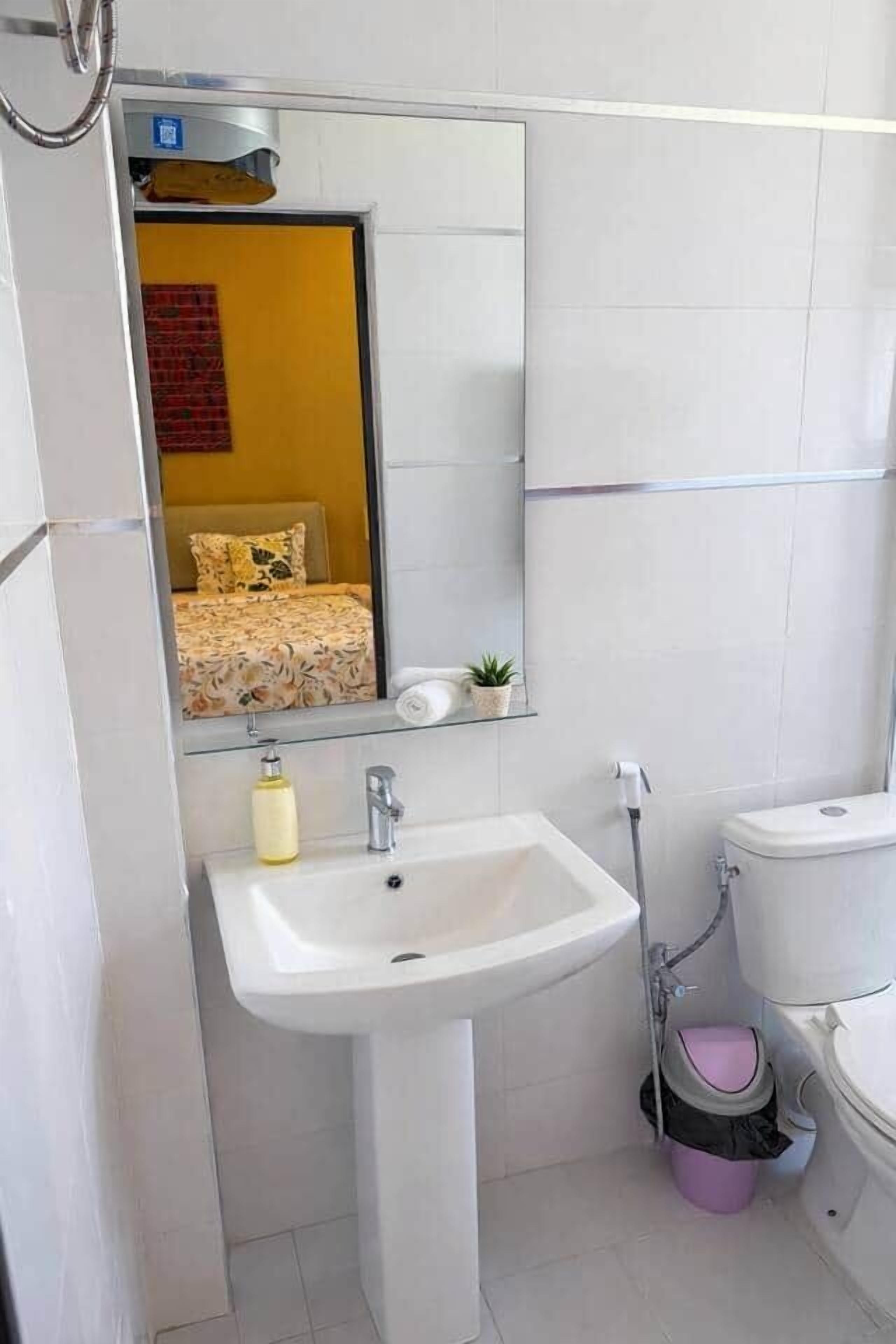 Een badkamer met een wit wastafel, een spiegel, een toilet en een douche.