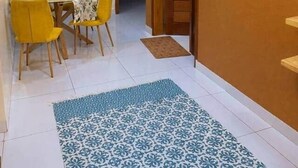 Ein Essbereich mit Tisch und Stühlen, einem gemusterten Teppich und einem Flur, der zu einer Tür führt.