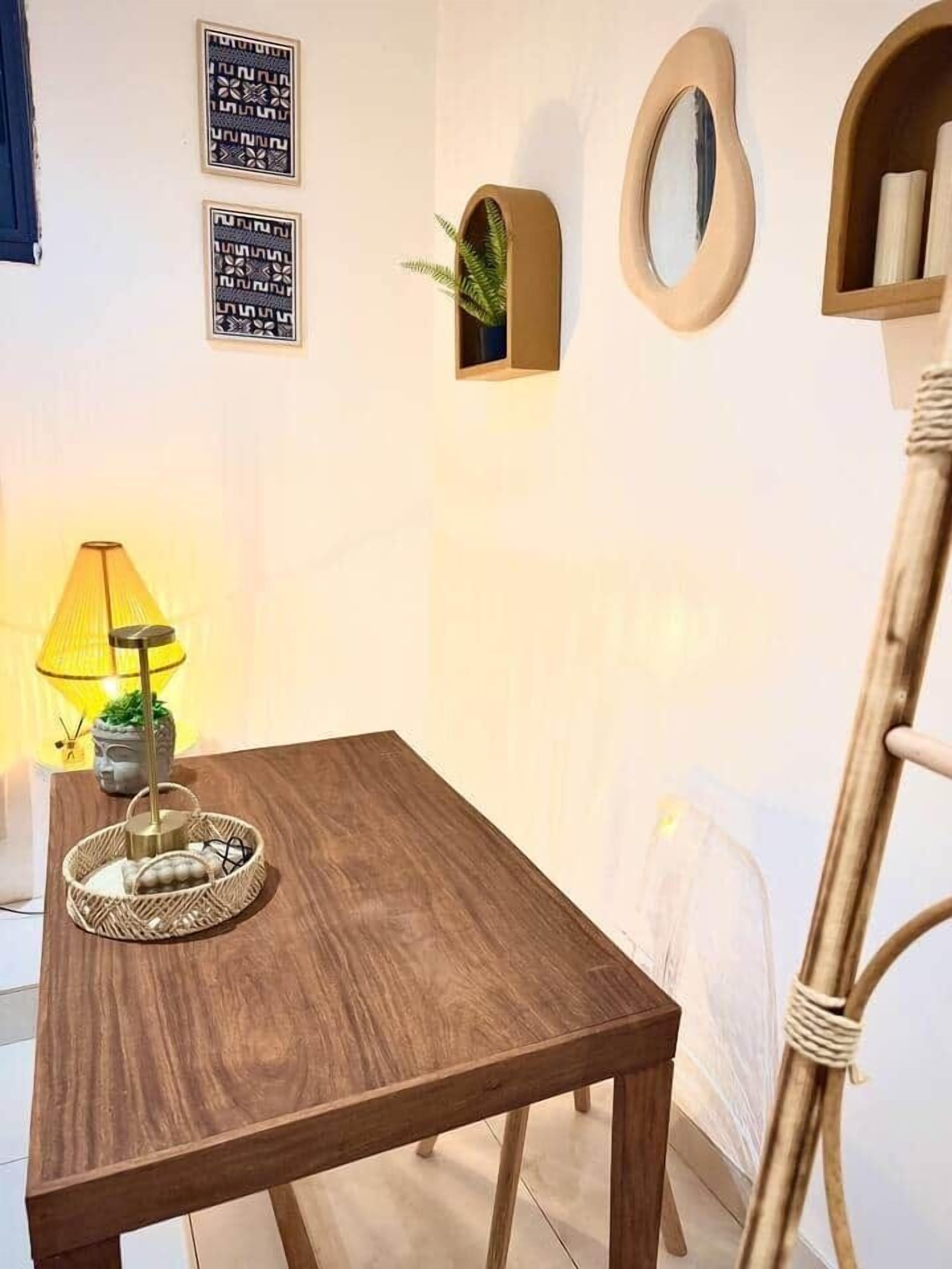 A wooden table with a woven basket, a lamp, and framed wall art.