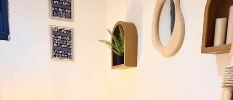A wooden table with a woven basket, a lamp, and framed wall art.
