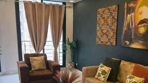 A modern living room with a sofa, armchair, and coffee table. - Spacious 2BR Almadies • Rooftop • Bright & Breezy (Dakar)