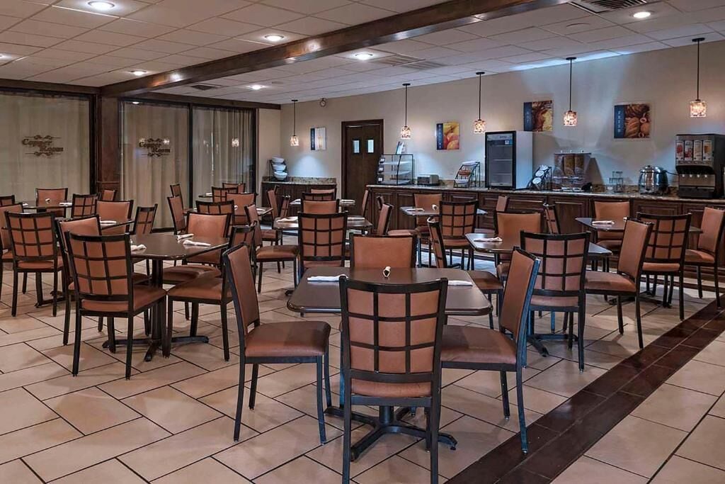 A restaurant with multiple tables and chairs, a counter with a coffee machine, and a wall with framed pictures.