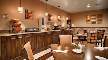 A hotel dining area with a central island, chairs, and tables.