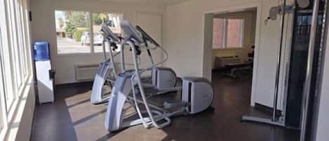 Une salle de sport équipée de tapis de course, de vélos elliptiques et d’appareils de musculation.