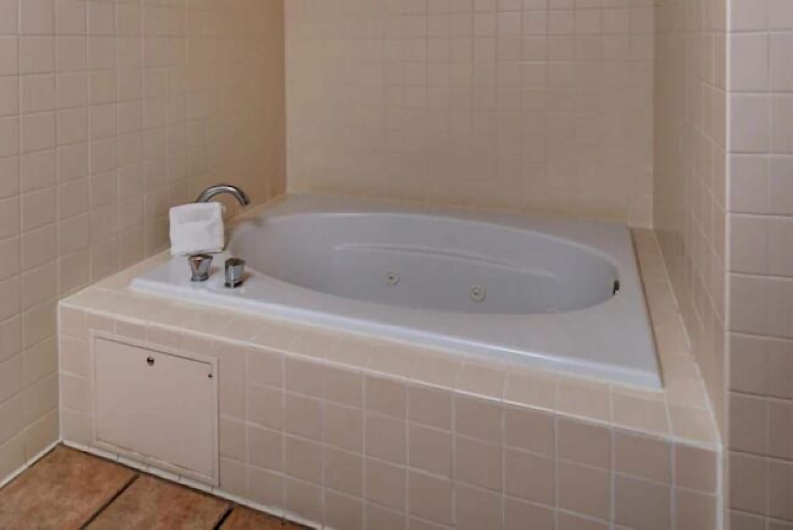 Un baño con bañera, toallero y panel de control de ducha.