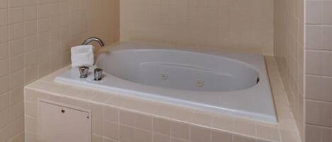 Un baño con bañera, toallero y panel de control de ducha.