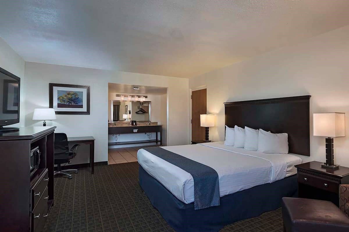 A hotel room with a bed, desk, chair, and a television.