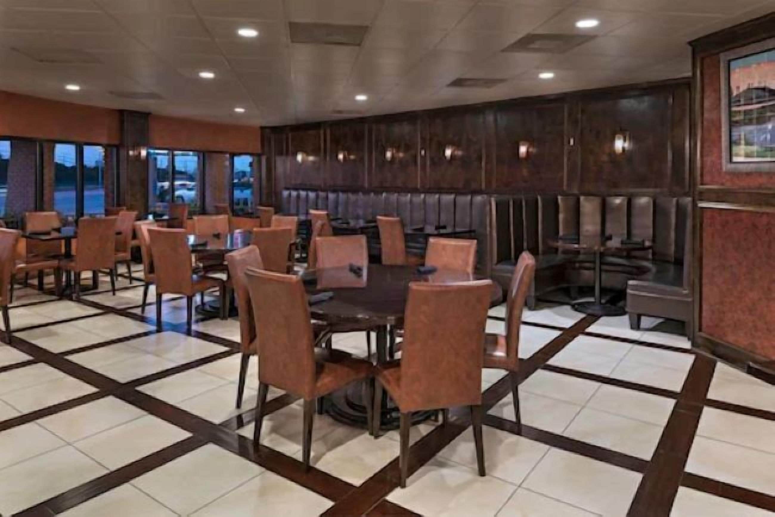 A restaurant with booths and tables, a tiled floor, and a view of the parking lot.