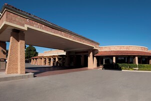 Um edifício com entrada coberta, colunas de tijolo e uma estrutura circular com telhado de telhas vermelhas.