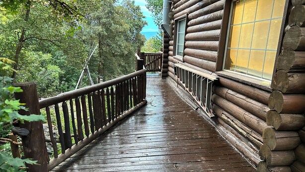 Eine Holzterrasse führt zu einer Blockhütte mit einem Fenster.