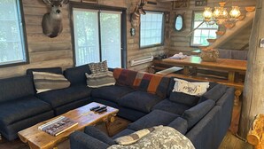Ein rustikales Holzhaus-Interieur mit einer Eckcouch, einem Holztisch und einem Esstisch.