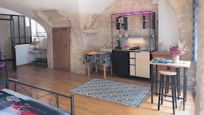 A cozy kitchen with a wooden table, bar stools, and a patterned rug.