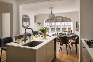 Une cuisine moderne dotée d’un îlot central, d’un coin repas et de grandes fenêtres.