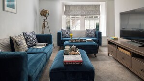 Un salon avec deux canapés bleus, une table basse, un téléviseur et une fenêtre donnant sur un beau paysage.