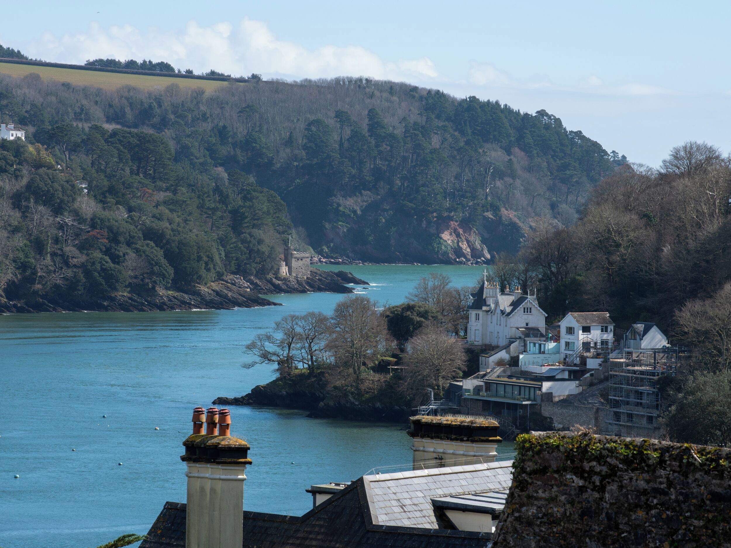 A coastal town with a river, houses, and a castle-like structure on a hill.