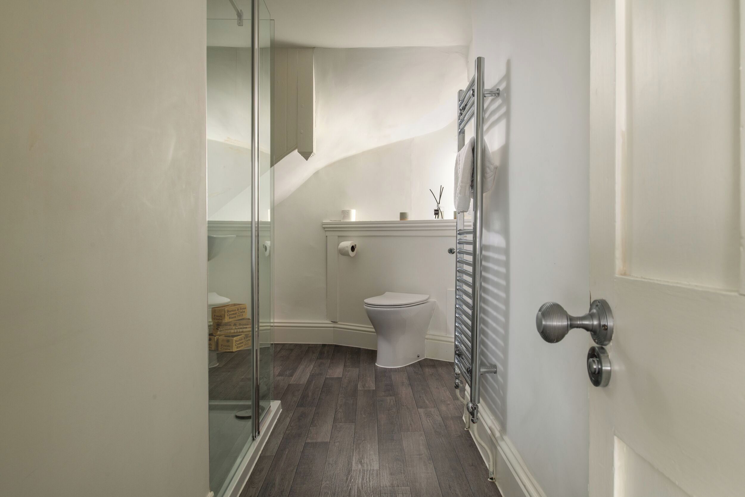 A bathroom with a toilet, a glass shower enclosure, and a towel rack.