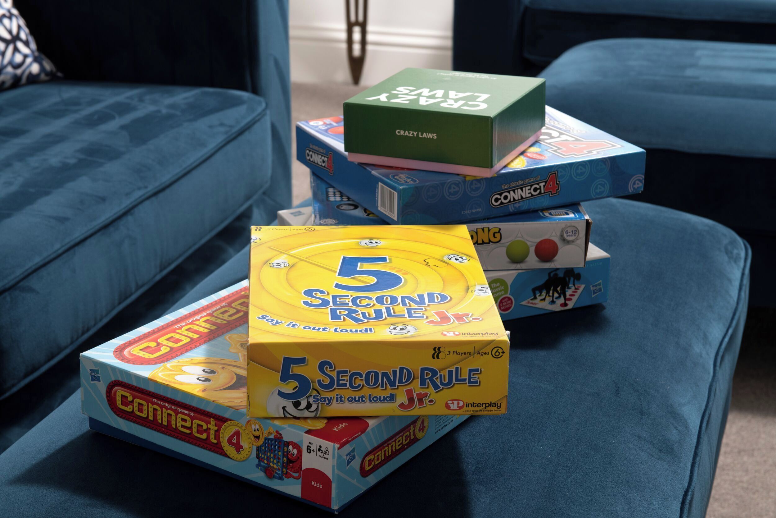 A stack of board games on a blue couch.