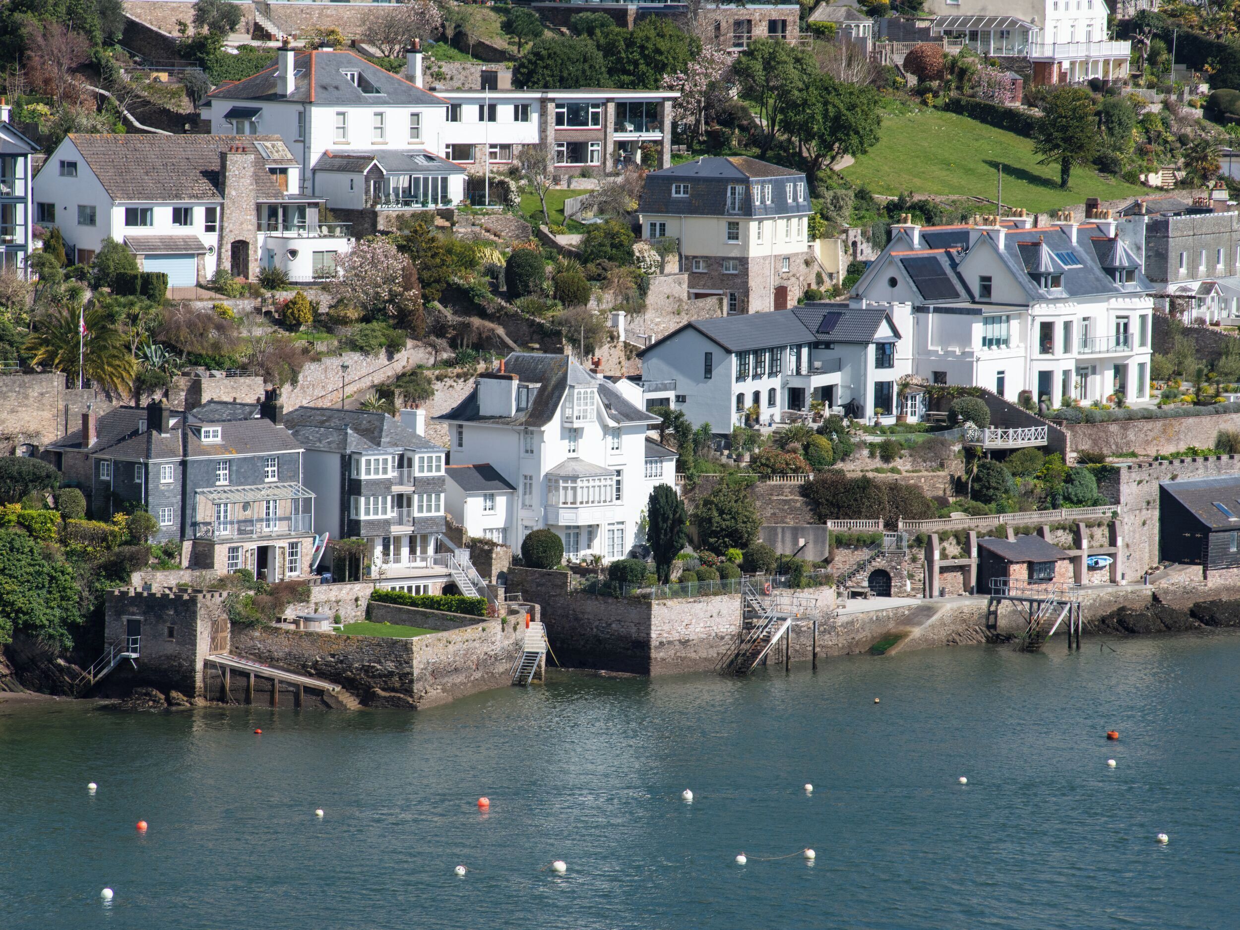 A coastal residential area with houses built on a hillside overlooking the sea.