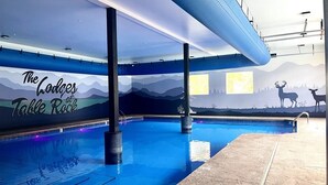 Una piscina interior con un mural de montañas y ciervos, identificada como "The Lodges at Table Rock".