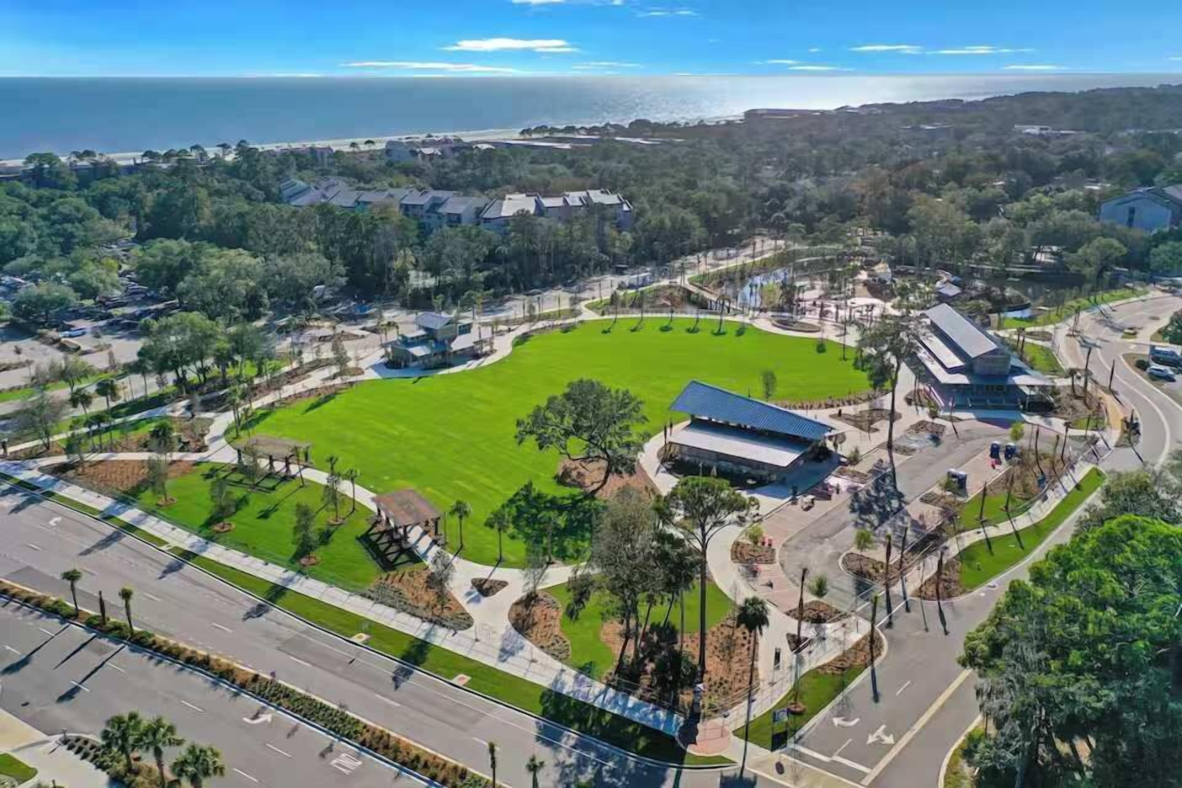 An aerial view of a campus with a central green field, buildings, and roads.