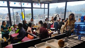 A communal dining area with tables, chairs, and a water dispenser. - HOSTAL SABAOTH (Quito)