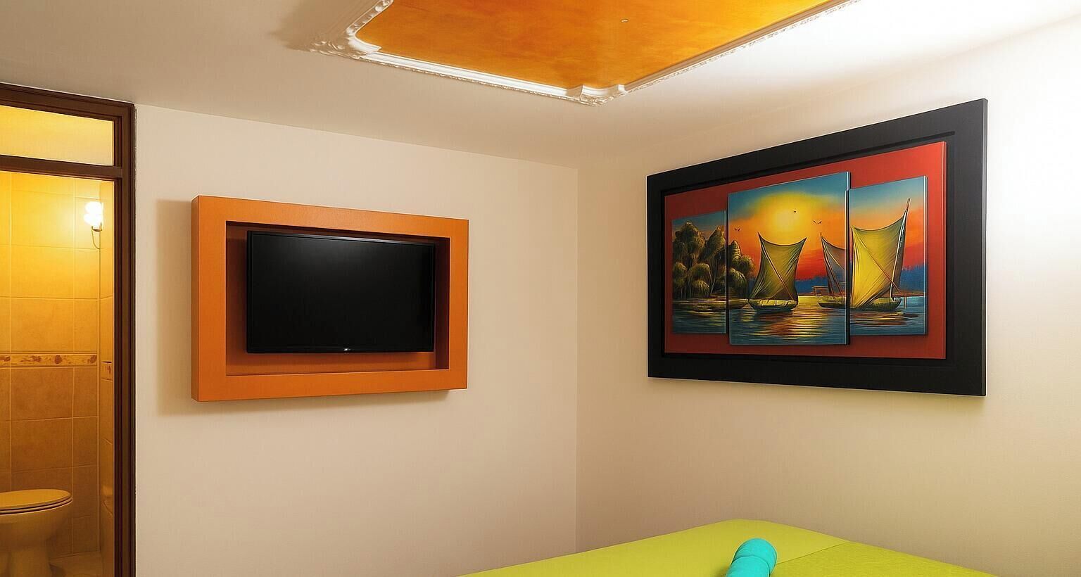 A room with a television mounted on the wall, a framed painting, and a green sofa.