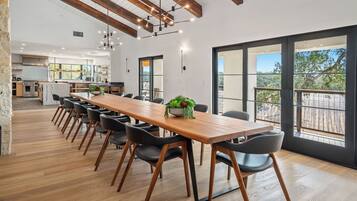 A spacious dining area with a long wooden table, black chairs, and a potted plant.