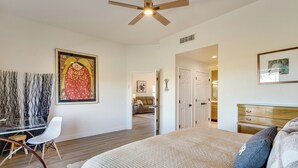 A bedroom with a bed, a desk, and a chair. There is a door leading to another room.