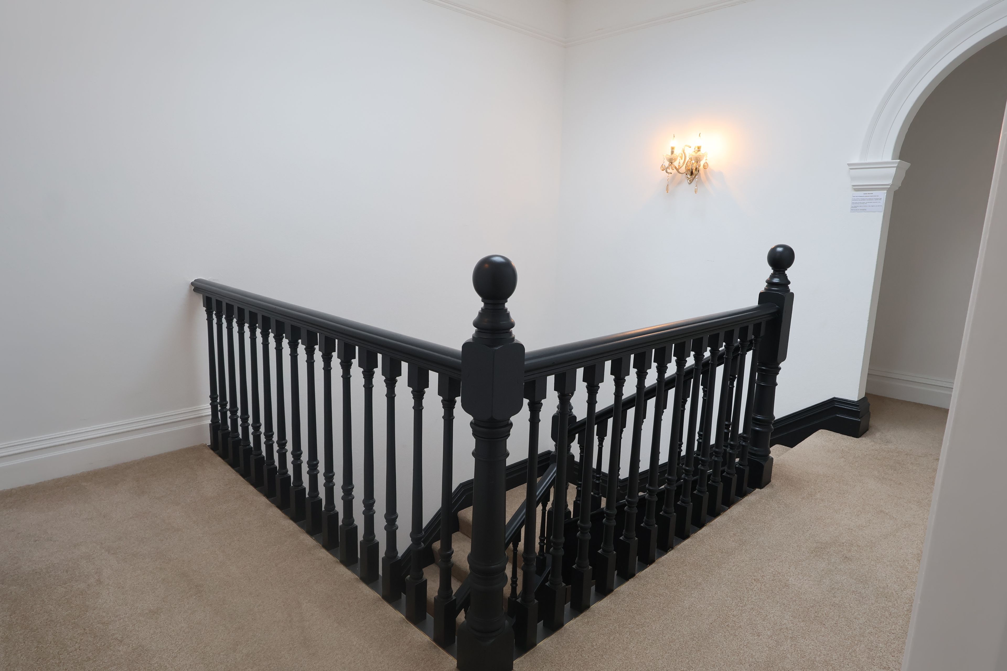 Eine Treppe mit schwarzen Stäben und einem beigen Teppich.