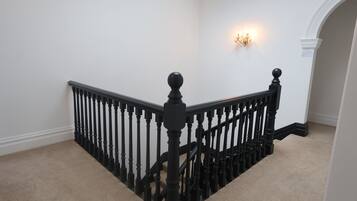 A staircase with black balusters and a beige carpet.