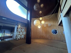 Ein modernes Interieur mit Holzwänden, einem großen, runden Dachfenster und hängenden, kugelförmigen Leuchten.