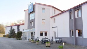 Hotel com design moderno, apresentando uma estufa de vidro e área externa com cadeiras e mesas.