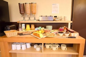 A breakfast buffet with various food items and beverages, including cereal, fruits, and coffee. - Kyriad Chambery La Ravoire (La Ravoire)