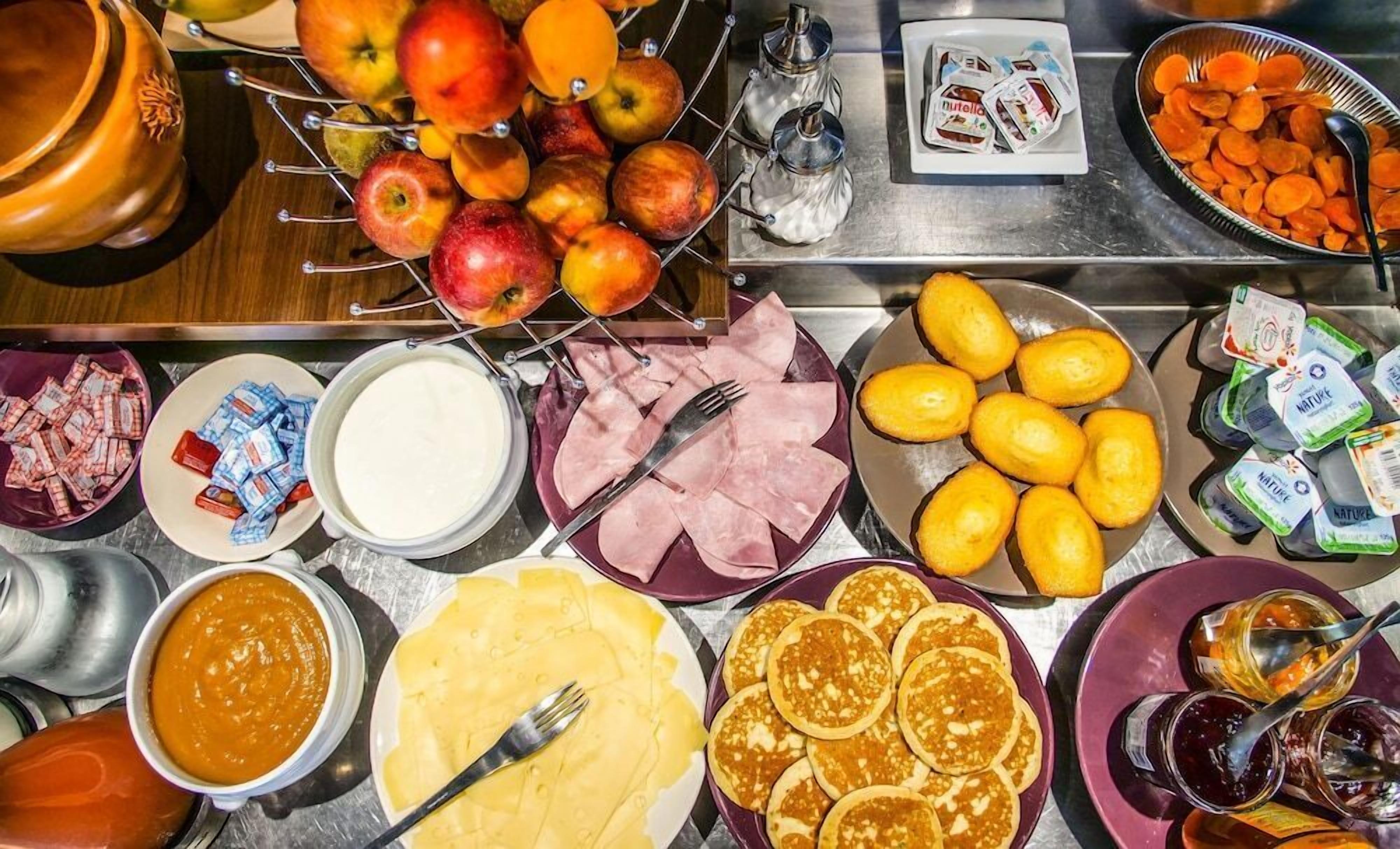 Ein Frühstücksbuffet mit verschiedenen Speisen, darunter Obst, Gebäck und Beilagen.