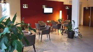 Uma sala de estar moderna com uma parede de destaque vermelha, assentos confortáveis e uma televisão de tela plana.