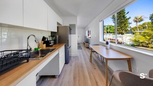 Een moderne keuken met een houten aanrecht, een roestvrijstalen spoelbak en uitzicht op een tuin door grote ramen.
