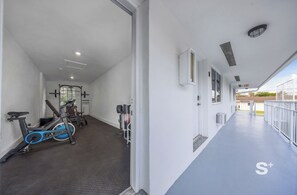 Une salle de sport équipée de matériel d’exercice, notamment un vélo d’exercice bleu et un tapis de course.
