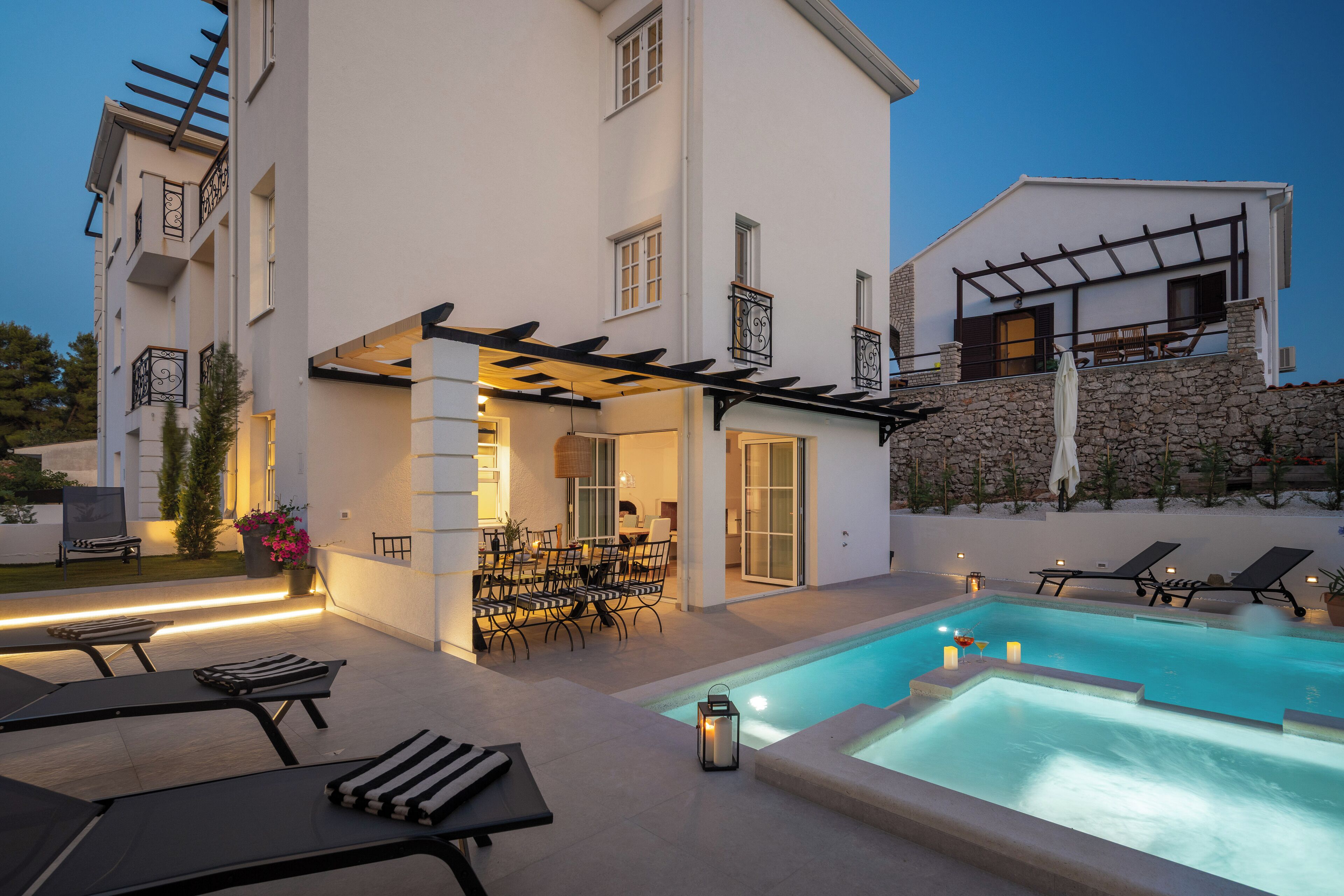 Une maison moderne dotée d’une piscine, d’un espace salon extérieur et d’une pergola.
