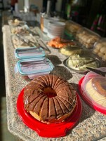 Uma mesa de buffet com diversos alimentos, incluindo um donut coberto de chocolate sobre um prato vermelho.