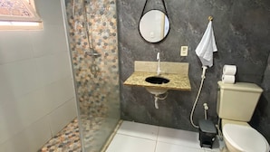 A bathroom with a shower, a sink, a toilet, and a mirror. - Novo Hotel Maracaipe (Ipojuca)