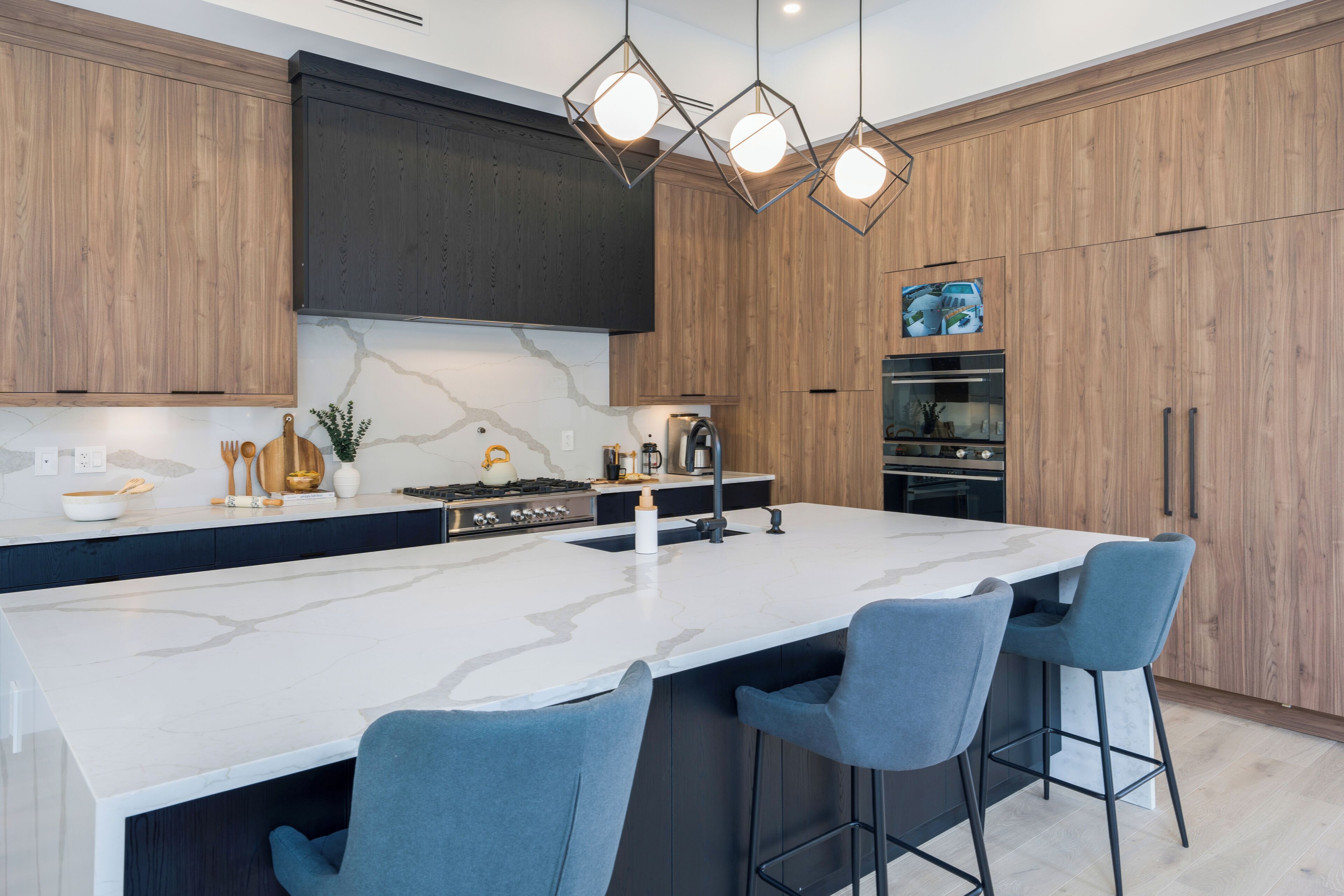 Una cocina moderna con una isla grande, taburetes de bar, armarios de madera y un horno empotrado.