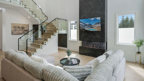 Uma sala de estar espaçosa com escada moderna, lareira e uma grande janela com vista para o exterior.